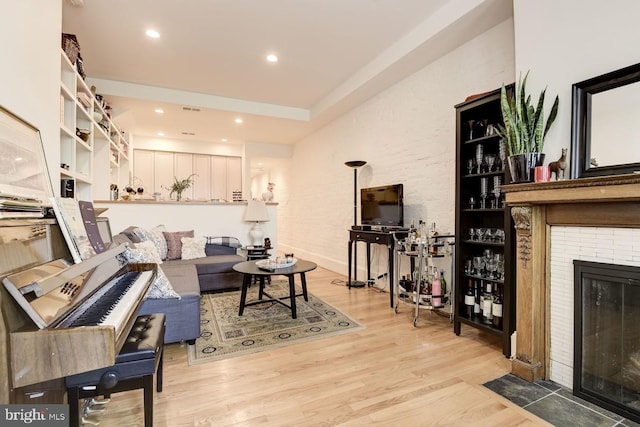 living room with light wood finished floors, a brick fireplace, visible vents, and recessed lighting