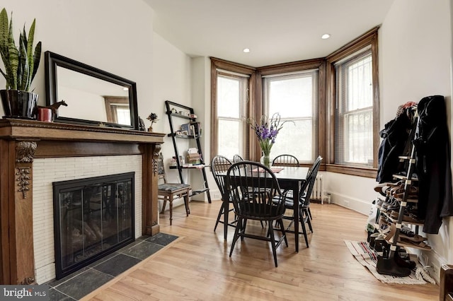 dining area with a brick fireplace, light wood-style floors, and recessed lighting