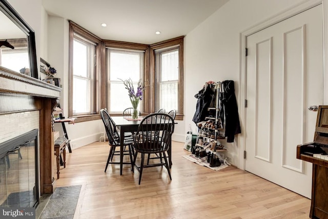 dining space featuring light wood-style floors, a brick fireplace, and baseboards