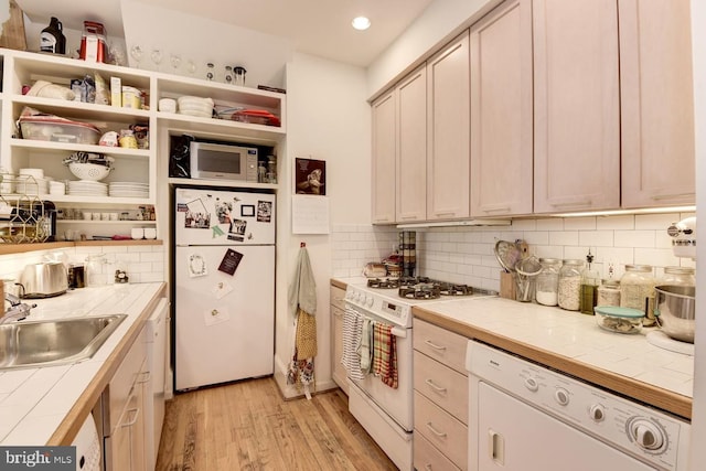 kitchen with open shelves, tile counters, light wood-style flooring, a sink, and white appliances