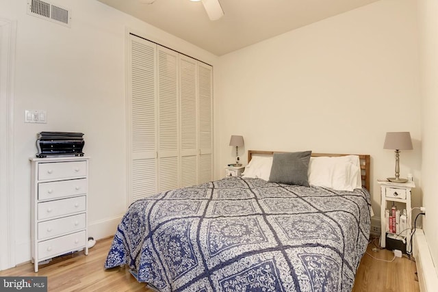 bedroom featuring visible vents, baseboards, a ceiling fan, light wood-style flooring, and a closet