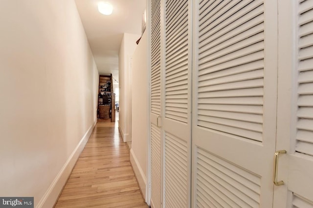 corridor featuring light wood-style flooring and baseboards