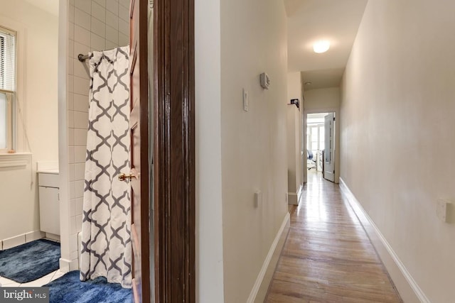 corridor featuring wood finished floors and baseboards