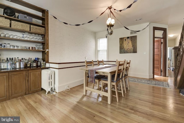 dining space with light wood-style floors, radiator, and baseboards