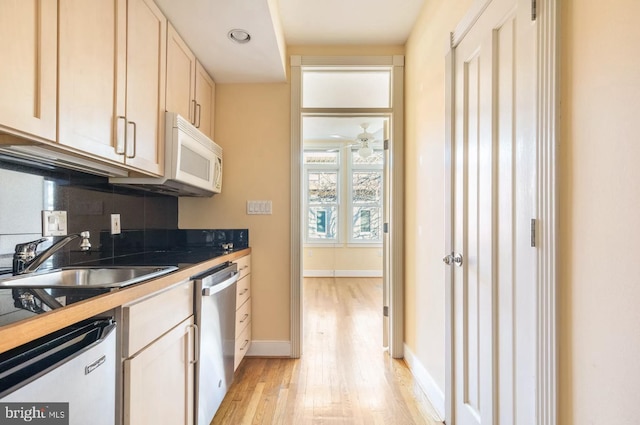 kitchen featuring dishwasher, dark countertops, dishwashing machine, white microwave, and a sink