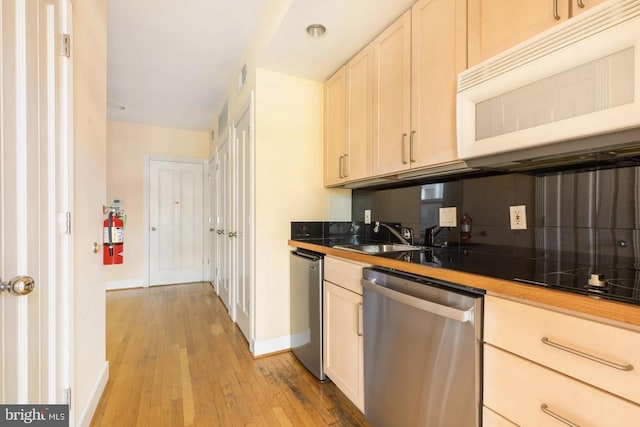 kitchen featuring light wood finished floors, visible vents, white microwave, stainless steel dishwasher, and a sink