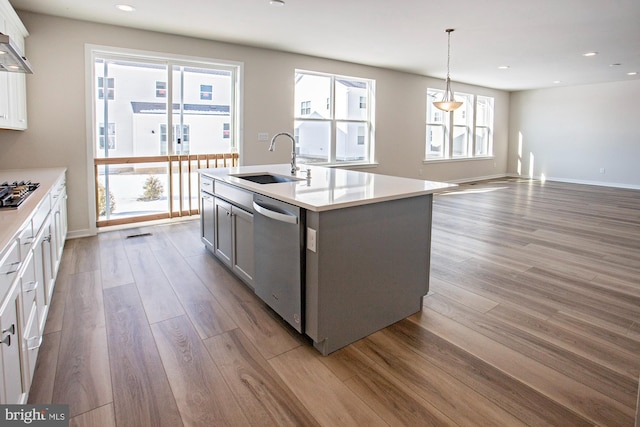 kitchen featuring a healthy amount of sunlight, appliances with stainless steel finishes, decorative light fixtures, and an island with sink