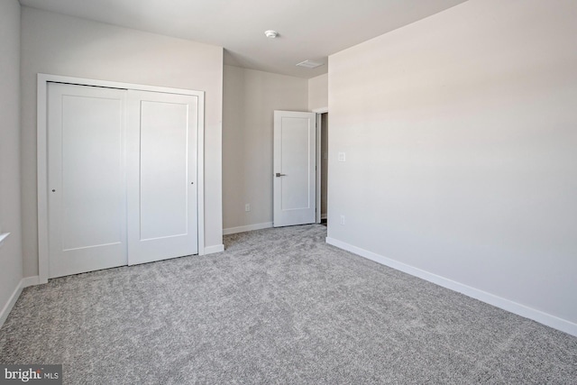 unfurnished bedroom featuring light colored carpet and a closet