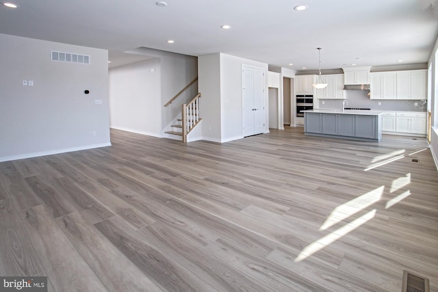 unfurnished living room featuring sink and light hardwood / wood-style floors