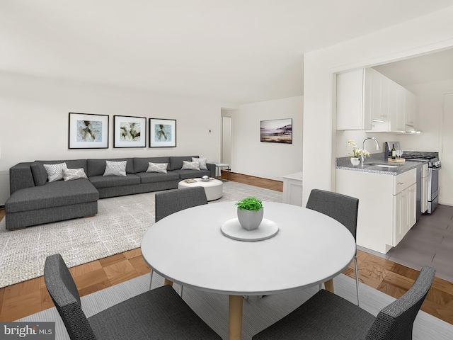 dining space featuring sink and dark parquet floors