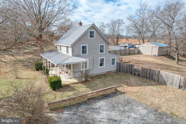 rear view of property featuring a patio area and a storage unit