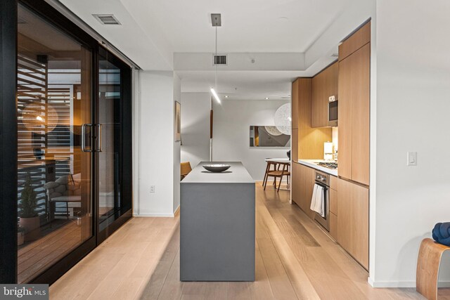 kitchen with hanging light fixtures, stainless steel gas cooktop, and light wood-type flooring