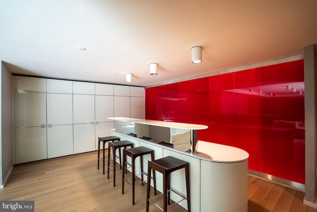 interior space with a kitchen breakfast bar, white cabinets, and light wood-type flooring