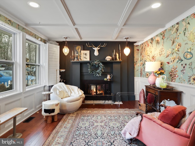 living area featuring a multi sided fireplace, ornamental molding, coffered ceiling, and dark hardwood / wood-style flooring