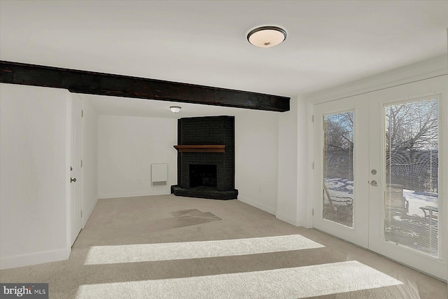 unfurnished living room featuring french doors, light colored carpet, a brick fireplace, and beamed ceiling