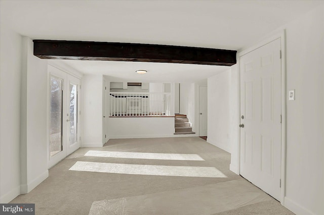 hall with beam ceiling and light colored carpet