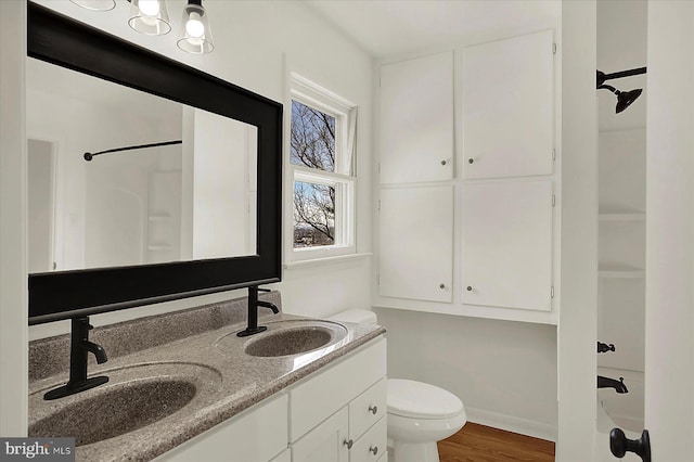 bathroom with hardwood / wood-style flooring, vanity, toilet, and walk in shower