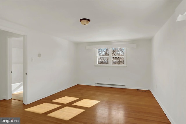 unfurnished room featuring hardwood / wood-style flooring and a baseboard heating unit