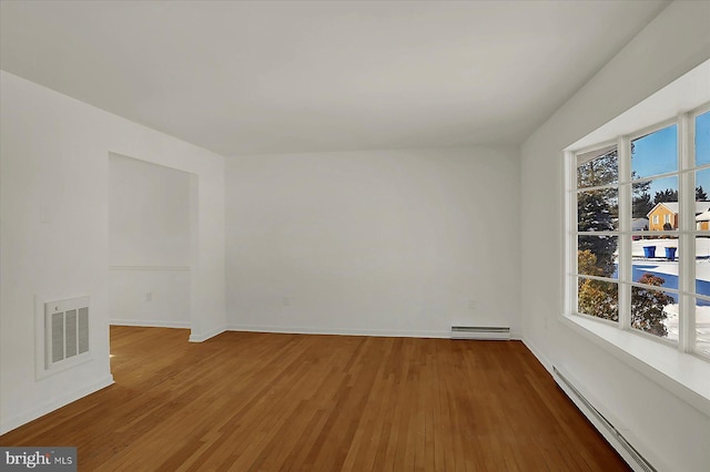 unfurnished room featuring a baseboard heating unit and wood-type flooring