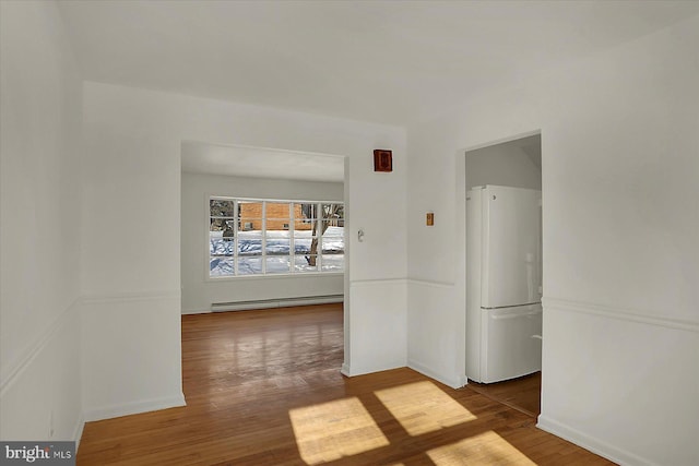 hall with a baseboard heating unit and hardwood / wood-style floors