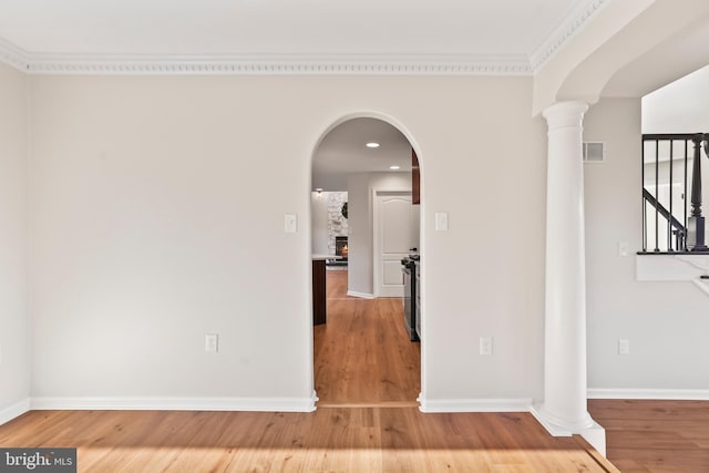 corridor with crown molding, wood-type flooring, and ornate columns