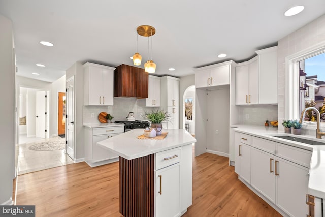 kitchen featuring sink, white cabinets, a center island, and hanging light fixtures