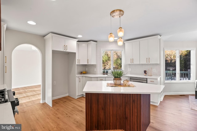 kitchen featuring dishwasher, decorative light fixtures, backsplash, white cabinetry, and light hardwood / wood-style floors