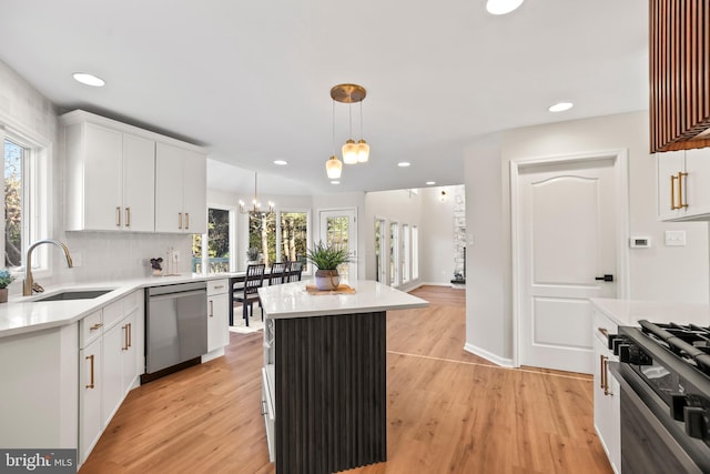 kitchen with sink, hanging light fixtures, white cabinets, and dishwasher