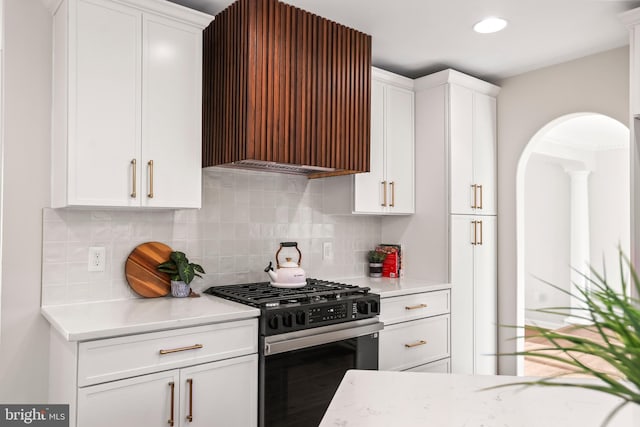 kitchen featuring range hood, white cabinetry, gas stove, and tasteful backsplash