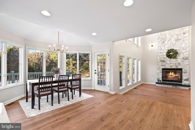 sunroom / solarium featuring a stone fireplace, a chandelier, and lofted ceiling