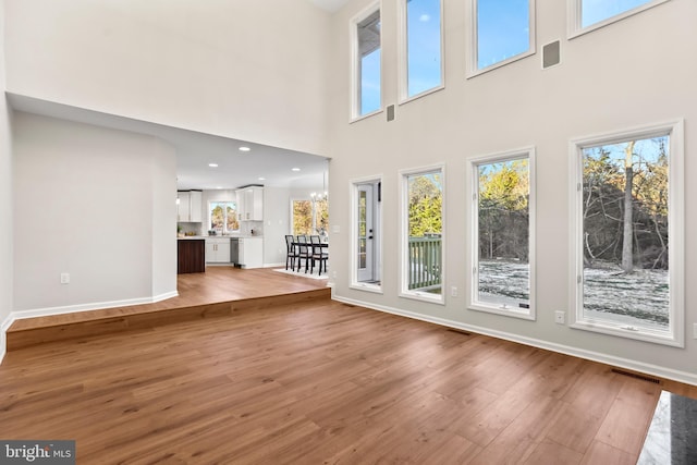 unfurnished living room with a notable chandelier, hardwood / wood-style flooring, and a high ceiling