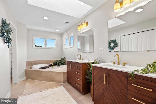 bathroom with tiled tub, tile patterned floors, vanity, and a skylight