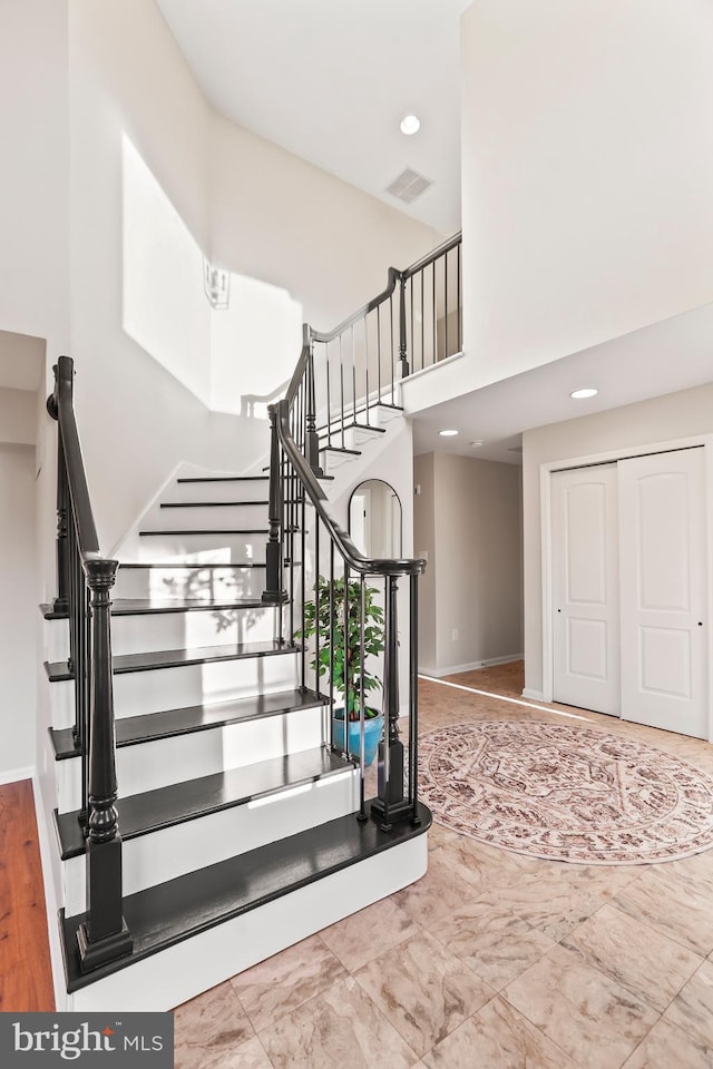 stairway featuring a towering ceiling