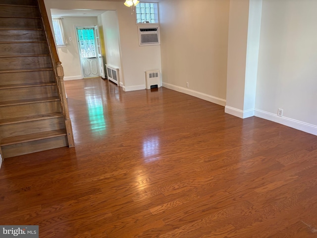 empty room with radiator heating unit, hardwood / wood-style floors, and an AC wall unit