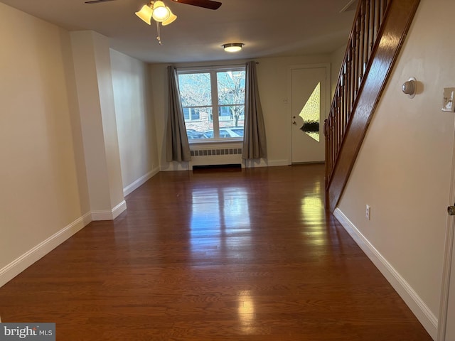 spare room featuring ceiling fan, dark wood-type flooring, and radiator