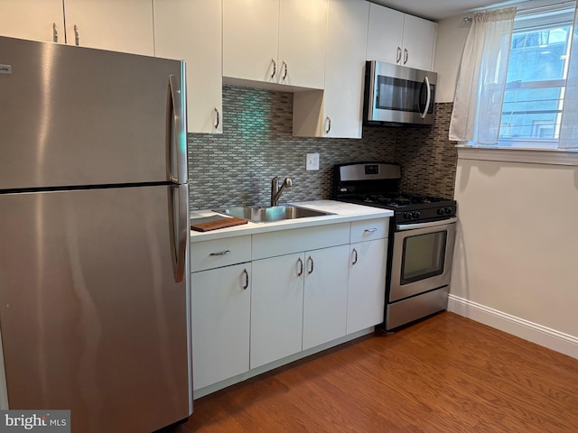 kitchen with tasteful backsplash, white cabinetry, sink, light hardwood / wood-style flooring, and stainless steel appliances