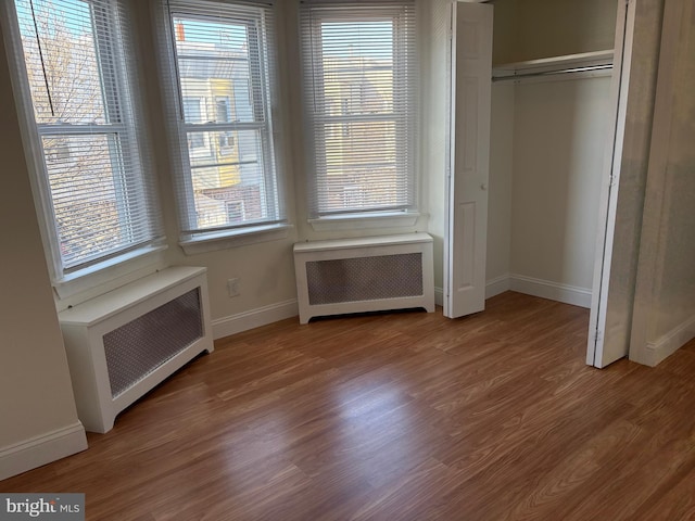 unfurnished bedroom featuring a closet, radiator heating unit, and wood-type flooring