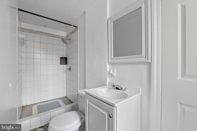 bathroom featuring vanity, a tile shower, and toilet