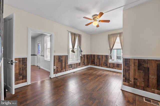 empty room featuring hardwood / wood-style flooring, ceiling fan, and wood walls