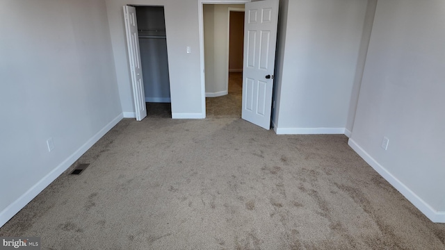 unfurnished bedroom featuring light colored carpet and a closet