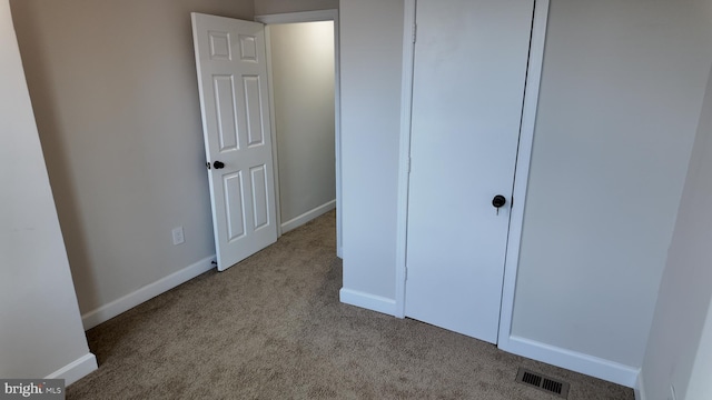 unfurnished bedroom with light colored carpet and a closet