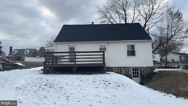 snow covered rear of property with a deck