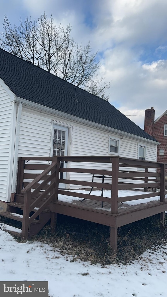 snow covered house with a wooden deck