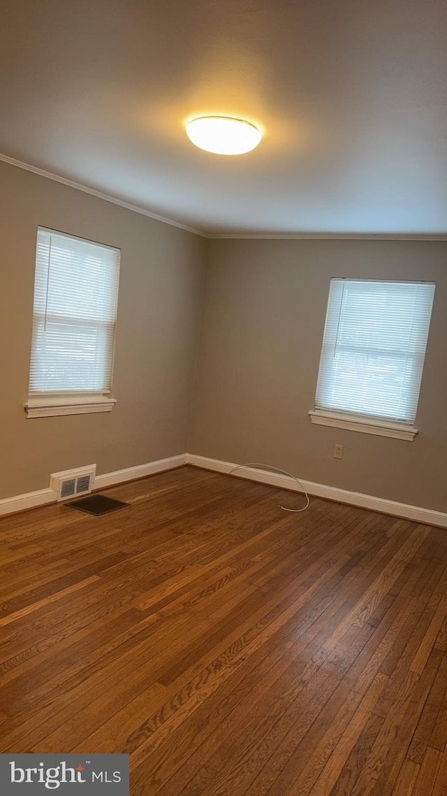 spare room with crown molding, plenty of natural light, and dark hardwood / wood-style floors