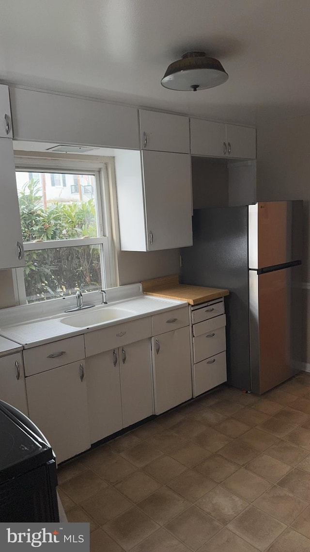 kitchen featuring white cabinetry, sink, and stainless steel fridge