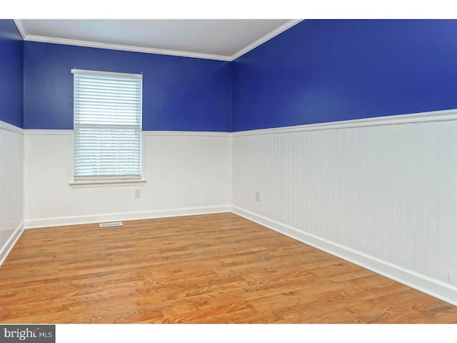 spare room with hardwood / wood-style flooring and crown molding