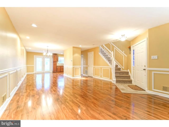 unfurnished living room with hardwood / wood-style floors and a notable chandelier