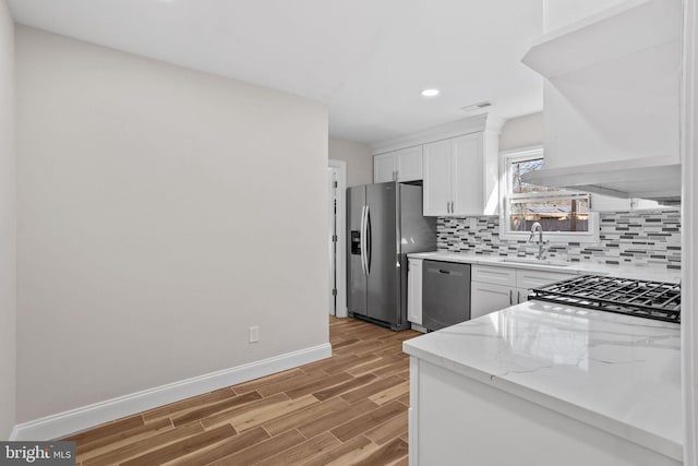 kitchen with sink, appliances with stainless steel finishes, white cabinetry, decorative backsplash, and light wood-type flooring