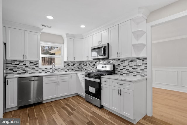 kitchen featuring hardwood / wood-style flooring, white cabinetry, appliances with stainless steel finishes, and sink