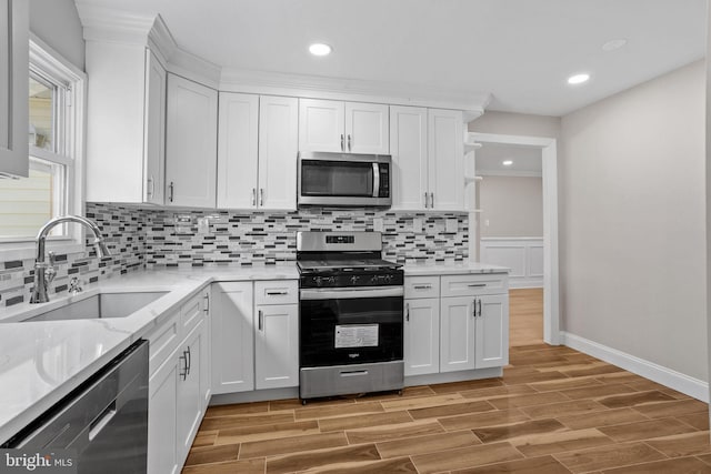 kitchen with stainless steel appliances, sink, white cabinets, and decorative backsplash